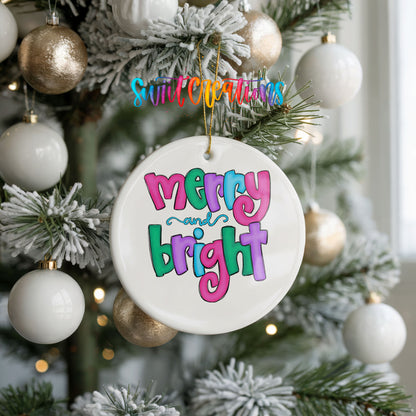 Round ceramic Christmas ornament featuring bright groovy Merry and Bright lettering in pink teal and purple, hanging on a frosted holiday tree