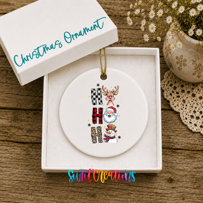 Round ceramic Christmas ornament featuring stacked Ho Ho Ho lettering with cheerful holiday characters, displayed in the included gift box