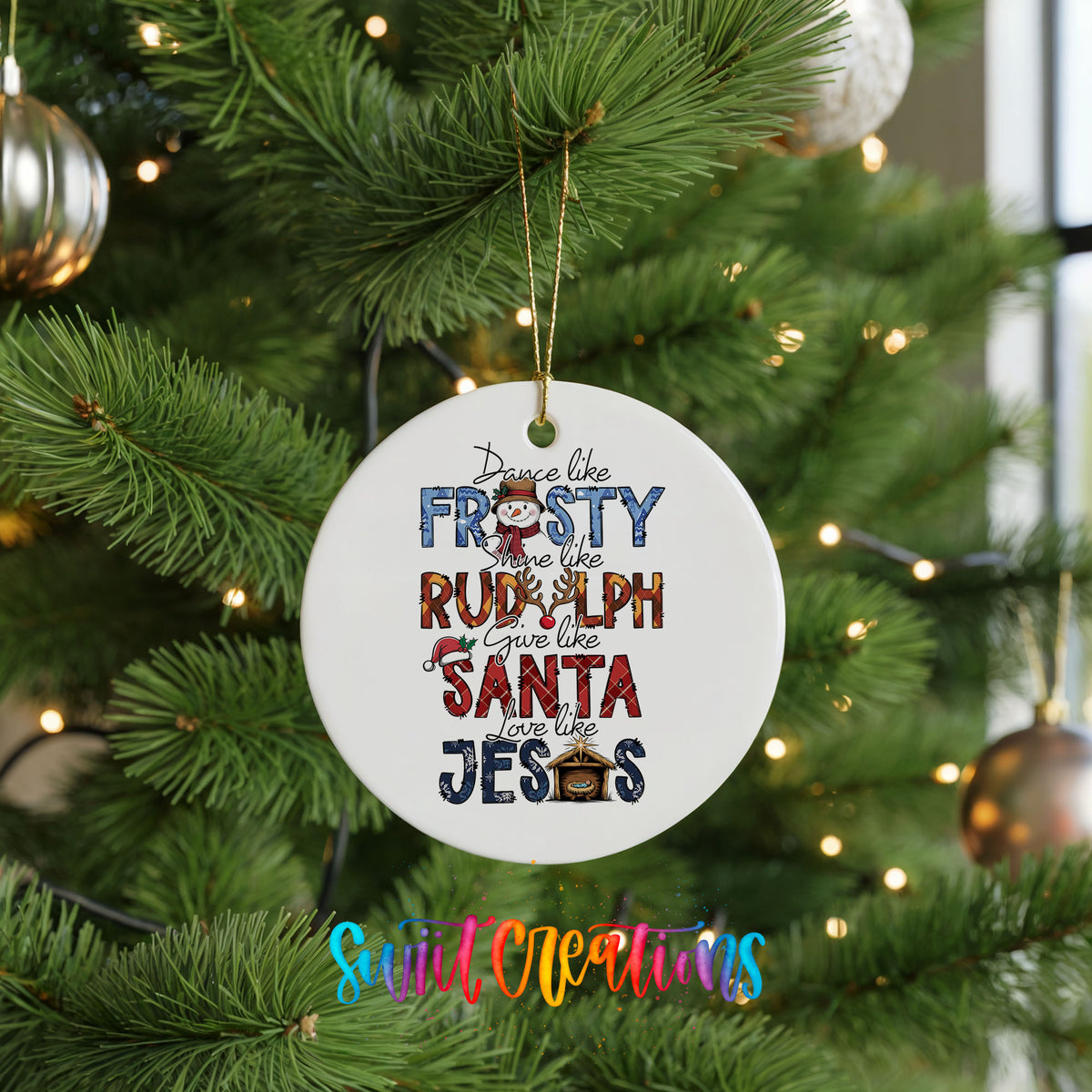 Round ceramic Christmas ornament featuring Dance like Frosty ride like Rudolph give like Santa love like Jesus message, hanging on a green Christmas tree