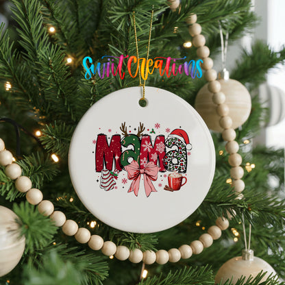 Round ceramic Christmas ornament featuring festive patterned Mama lettering with a large red holiday bow, hanging on a decorated Christmas tree