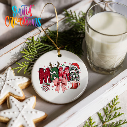 Round ceramic Christmas ornament featuring festive patterned Mama lettering with a large red holiday bow, styled with cookies and milk