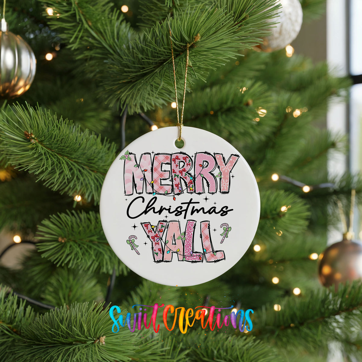 Round ceramic Christmas ornament featuring patterned Merry Christmas Y’all lettering with pink and green accents, hanging on a green Christmas tree