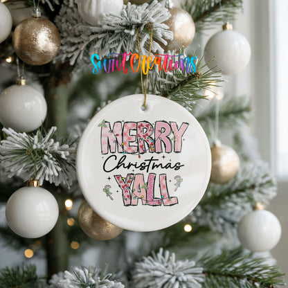 Round ceramic Christmas ornament featuring patterned Merry Christmas Y’all lettering with pink and green accents, hanging on a frosted holiday tree