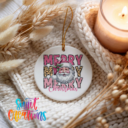 Round ceramic Christmas ornament featuring stacked Merry Merry Merry Christmas lettering with Santa and leopard print accents, styled beside a candle and cozy knit blanket