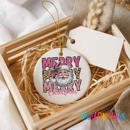 Round ceramic Christmas ornament featuring stacked Merry Merry Merry Christmas lettering with Santa and leopard print accents, presented in a rustic wooden gift crate