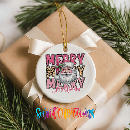 Round ceramic Christmas ornament featuring stacked Merry Merry Merry Christmas lettering with Santa and leopard print accents, placed on a wrapped Christmas gift