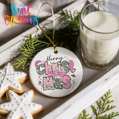 Round ceramic Christmas ornament featuring stacked patterned Merry Christmas lettering in pink green and black, styled with cookies and milk