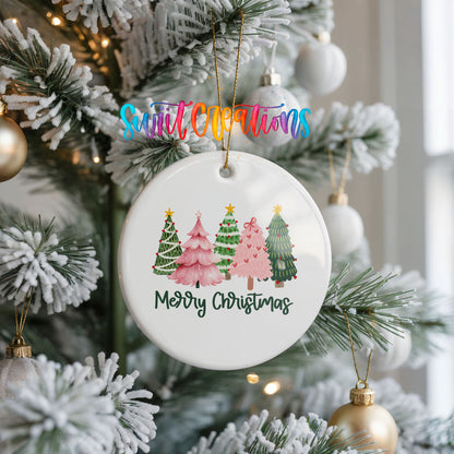 Round ceramic Christmas ornament featuring row of whimsical colorful Christmas trees with Merry Christmas script, hanging on a frosted Christmas tree