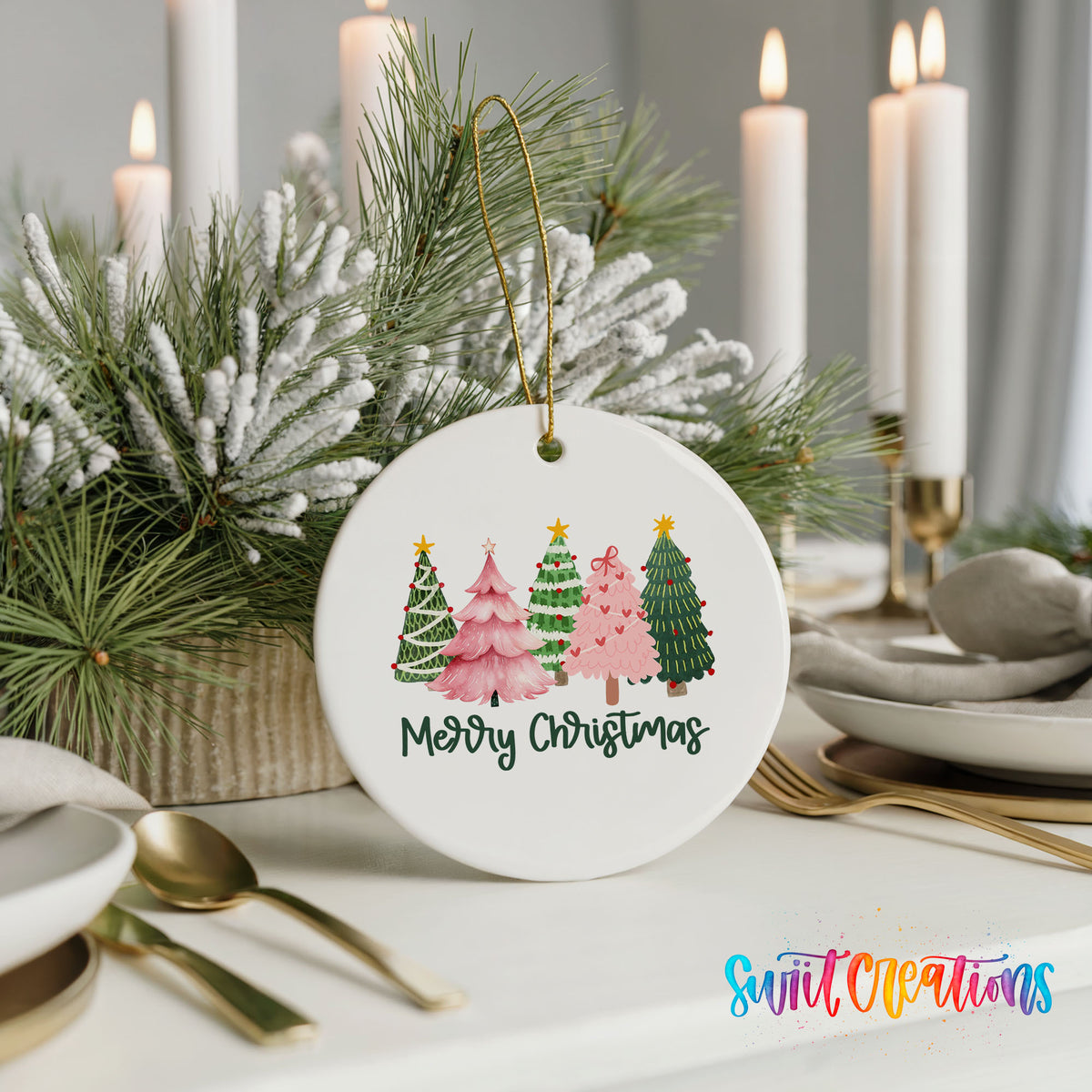 Round ceramic Christmas ornament featuring row of whimsical colorful Christmas trees with Merry Christmas script, styled with elegant holiday table decor
