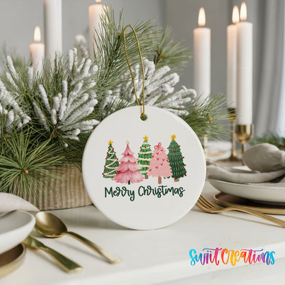 Round ceramic Christmas ornament featuring row of whimsical colorful Christmas trees with Merry Christmas script, styled with elegant holiday table decor