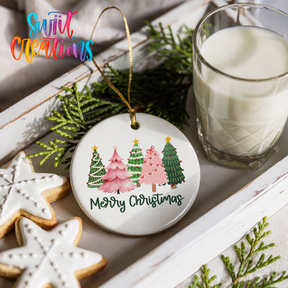 Round ceramic Christmas ornament featuring row of whimsical colorful Christmas trees with Merry Christmas script, styled with cookies and milk