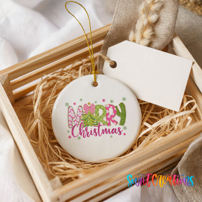 Round ceramic Christmas ornament featuring bright Merry Christmas lettering with candy stripe and floral details, presented in a rustic wooden gift crate