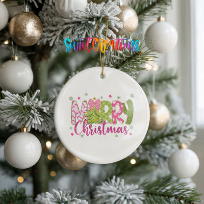 Round ceramic Christmas ornament featuring bright Merry Christmas lettering with candy stripe and floral details, hanging on a frosted holiday tree