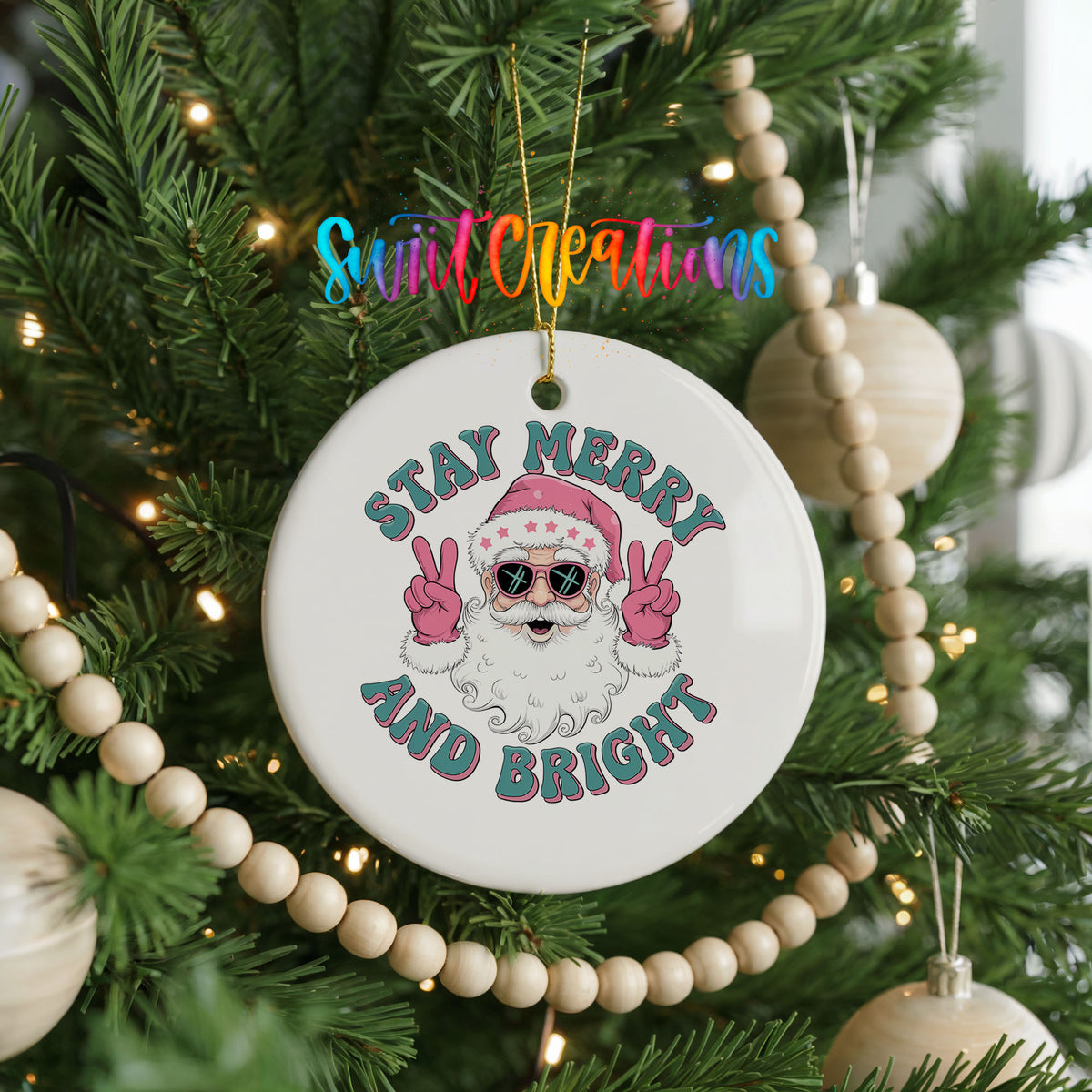 Round ceramic Christmas ornament featuring Santa in sunglasses giving peace signs with Stay Merry and Bright lettering, hanging on a decorated Christmas tree