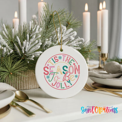 Round ceramic Christmas ornament featuring round pastel ’Tis the Season to Be Jolly holiday typography, styled with elegant holiday table decor