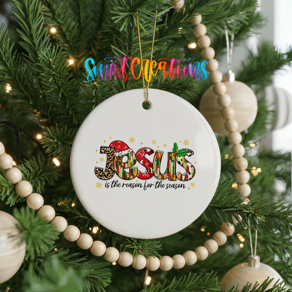 Round ceramic Christmas ornament featuring colorful Jesus Is the Reason for the Season typography, hanging on a decorated Christmas tree