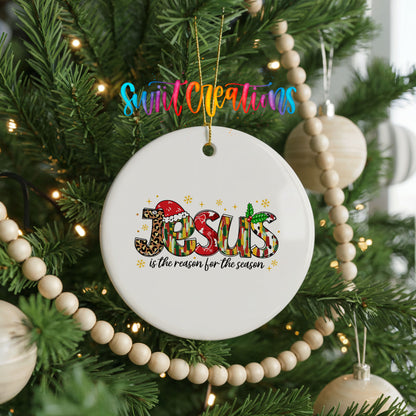 Round ceramic Christmas ornament featuring colorful Jesus Is the Reason for the Season typography, hanging on a decorated Christmas tree