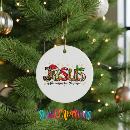 Round ceramic Christmas ornament featuring colorful Jesus Is the Reason for the Season typography, hanging on a green Christmas tree