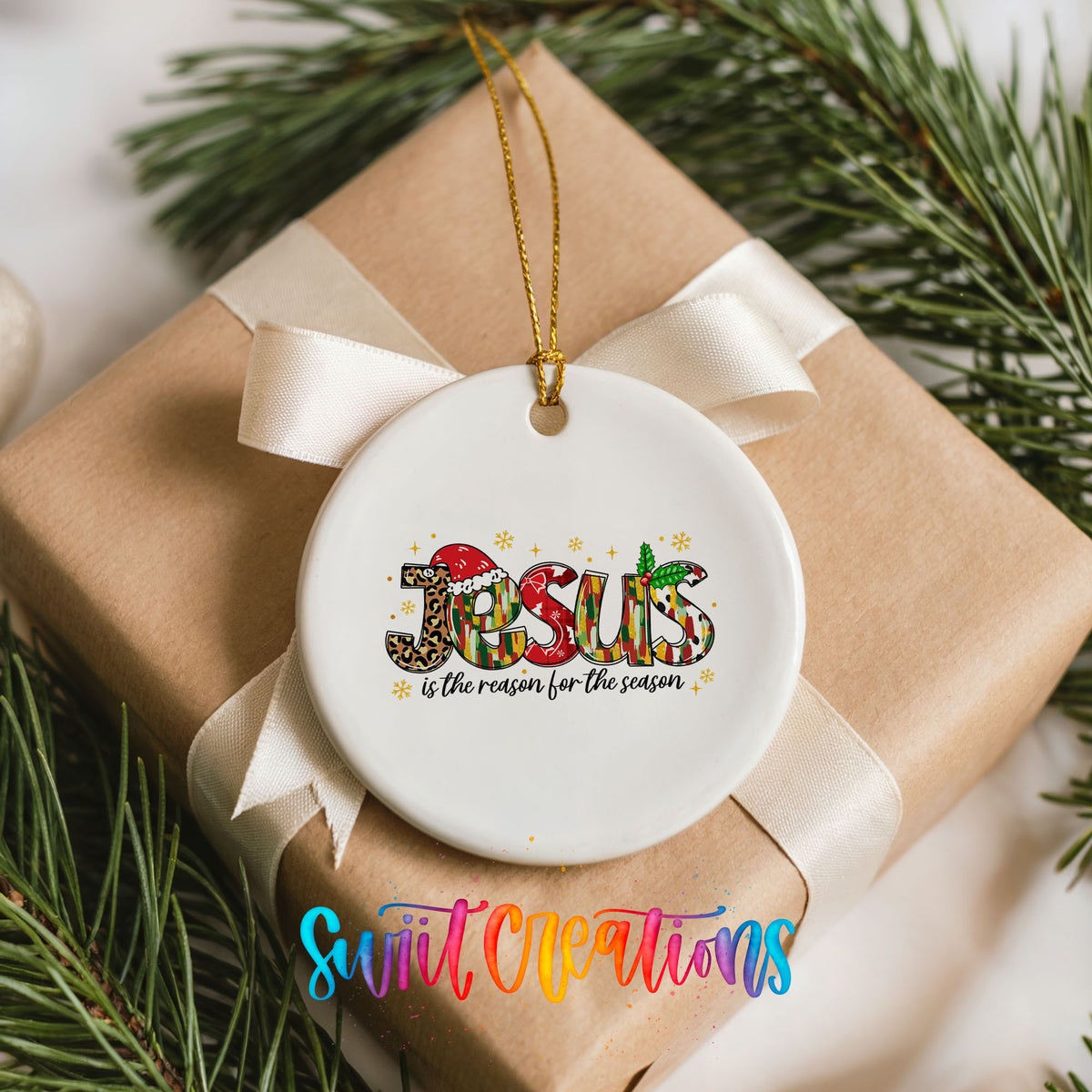 Round ceramic Christmas ornament featuring colorful Jesus Is the Reason for the Season typography, placed on a wrapped Christmas gift