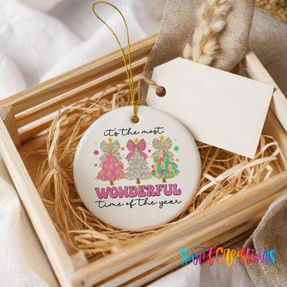 Round ceramic Christmas ornament featuring It’s the Most Wonderful Time of the Year lettering with colorful gifts and trees, presented in a rustic wooden gift crate