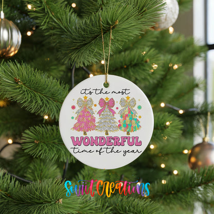 Round ceramic Christmas ornament featuring It’s the Most Wonderful Time of the Year lettering with colorful gifts and trees, hanging on a green Christmas tree