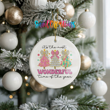 Round ceramic Christmas ornament featuring It’s the Most Wonderful Time of the Year lettering with colorful gifts and trees, hanging on a frosted holiday tree