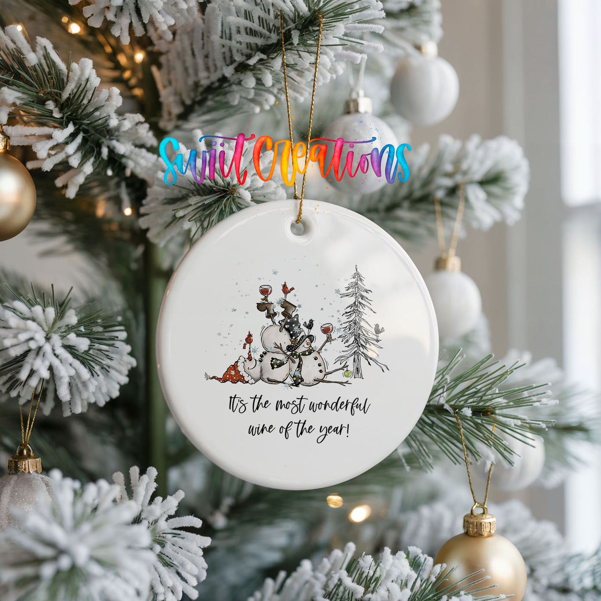 Round ceramic Christmas ornament featuring tipsy snowmen with wine glasses and It’s the Most Wonderful Wine of the Year lettering, hanging on a frosted Christmas tree