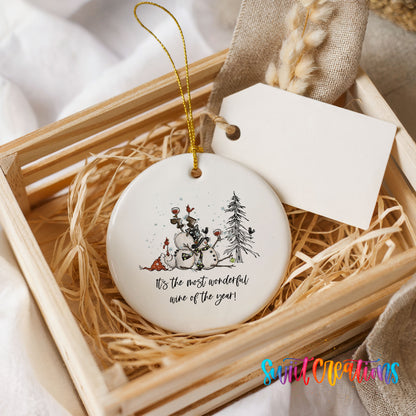 Round ceramic Christmas ornament featuring tipsy snowmen with wine glasses and It’s the Most Wonderful Wine of the Year lettering, presented in a rustic wooden gift crate