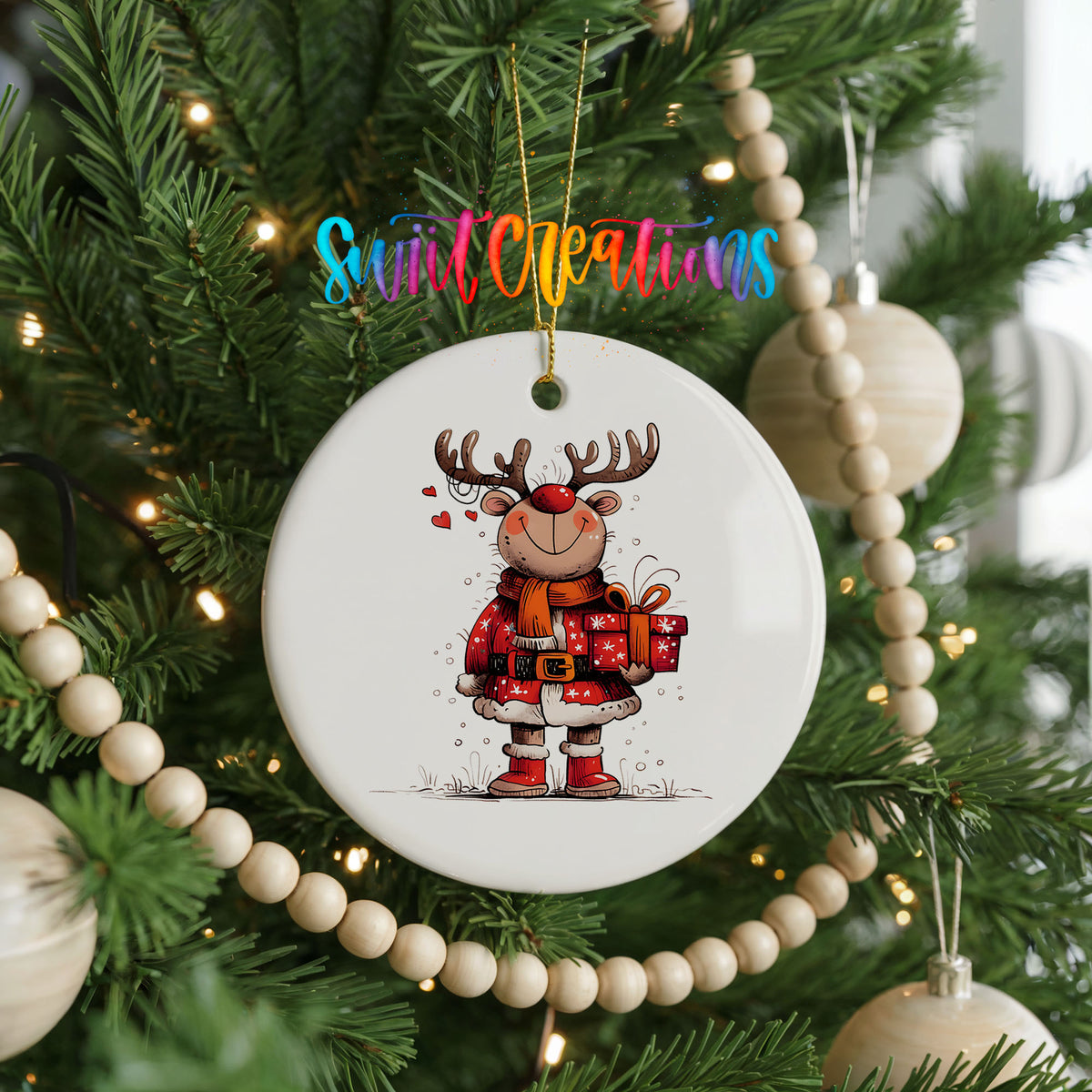 Round ceramic Christmas ornament featuring cheerful reindeer in a Santa suit holding wrapped Christmas gifts, hanging on a decorated Christmas tree