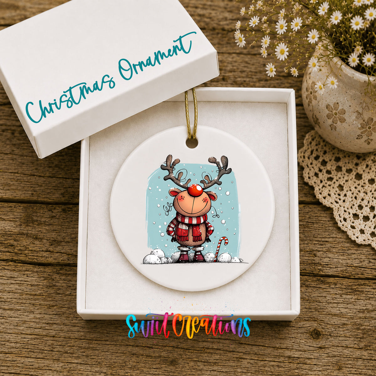 Round ceramic Christmas ornament featuring smiling reindeer in red plaid winter clothes against a snowy blue background, displayed in the included gift box