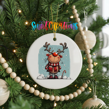 Round ceramic Christmas ornament featuring smiling reindeer in red plaid winter clothes against a snowy blue background, hanging on a decorated Christmas tree