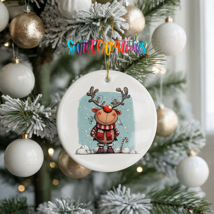 Round ceramic Christmas ornament featuring smiling reindeer in red plaid winter clothes against a snowy blue background, hanging on a frosted holiday tree