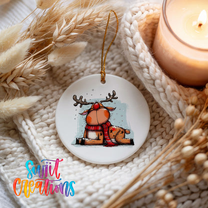 Santa and Reindeer with Gift Sack Christmas ornament styled beside a candle and cozy knit blanket
