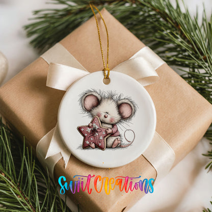 pink mouse holding a star ceramic Christmas ornament displayed on a wrapped Christmas gift