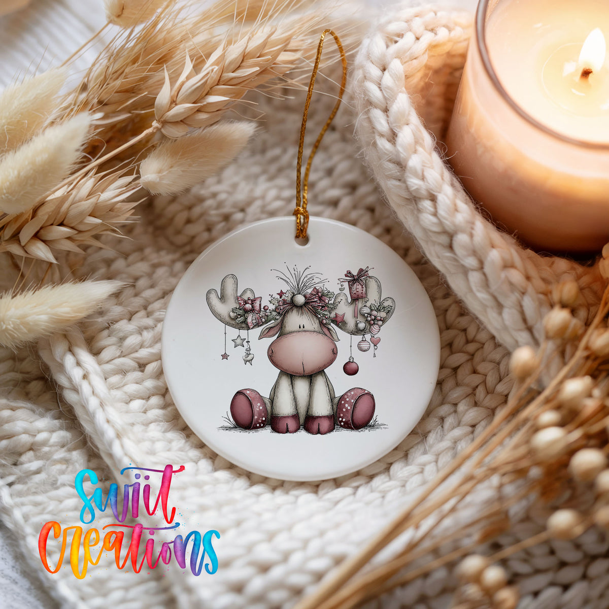pink reindeer with decorated antlers ceramic Christmas ornament styled on a cozy knit blanket