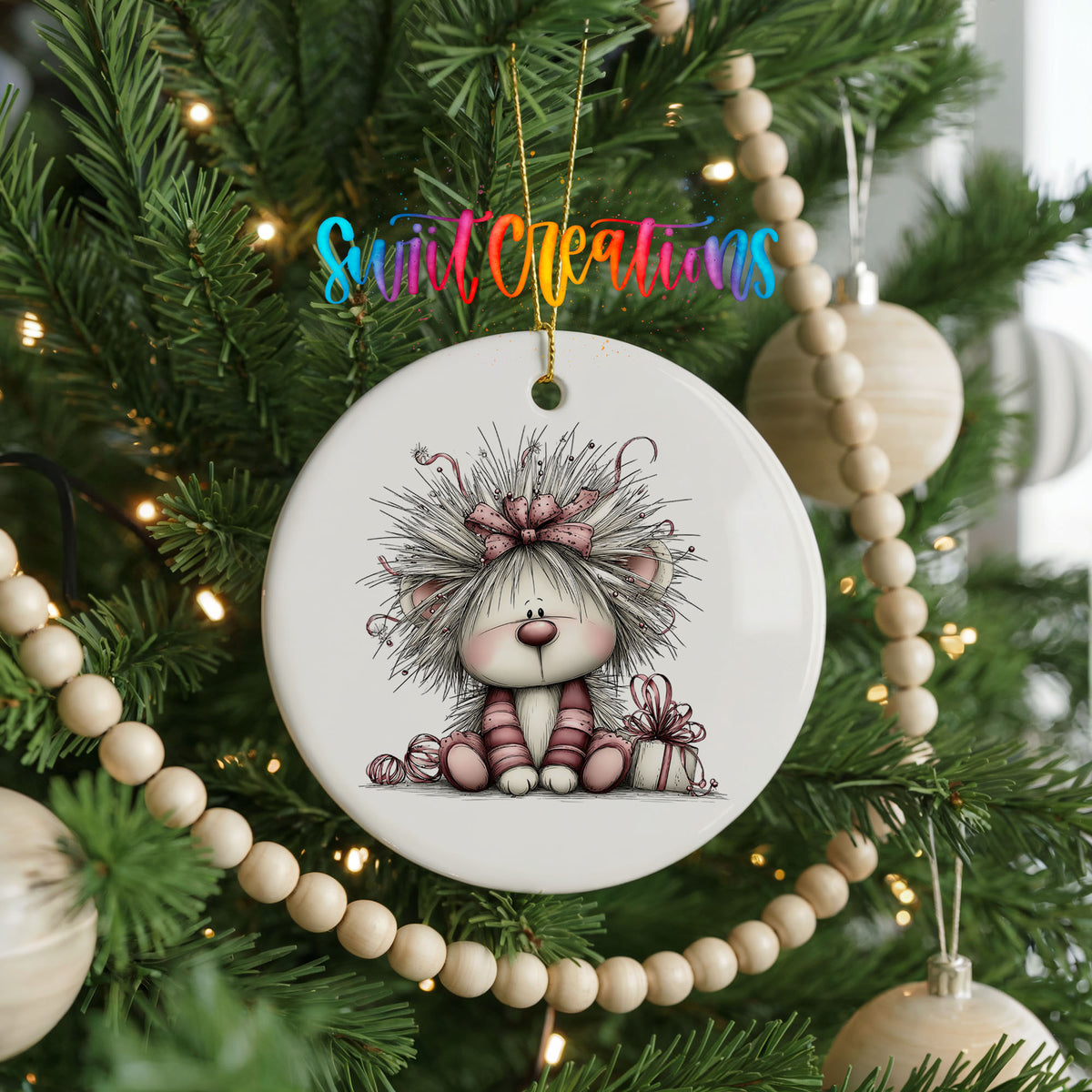white and pink kitten in a floral winter headpiece ceramic Christmas ornament hanging on a green Christmas tree