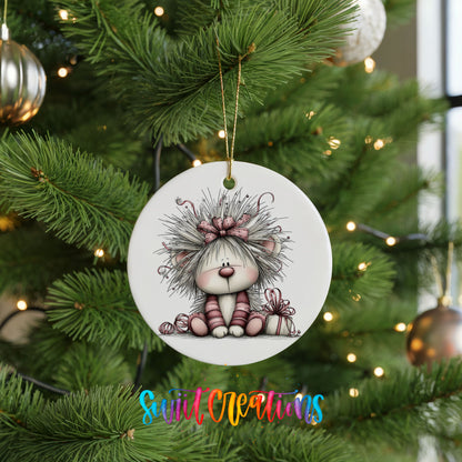 white and pink kitten in a floral winter headpiece ceramic Christmas ornament hanging on a lit Christmas tree