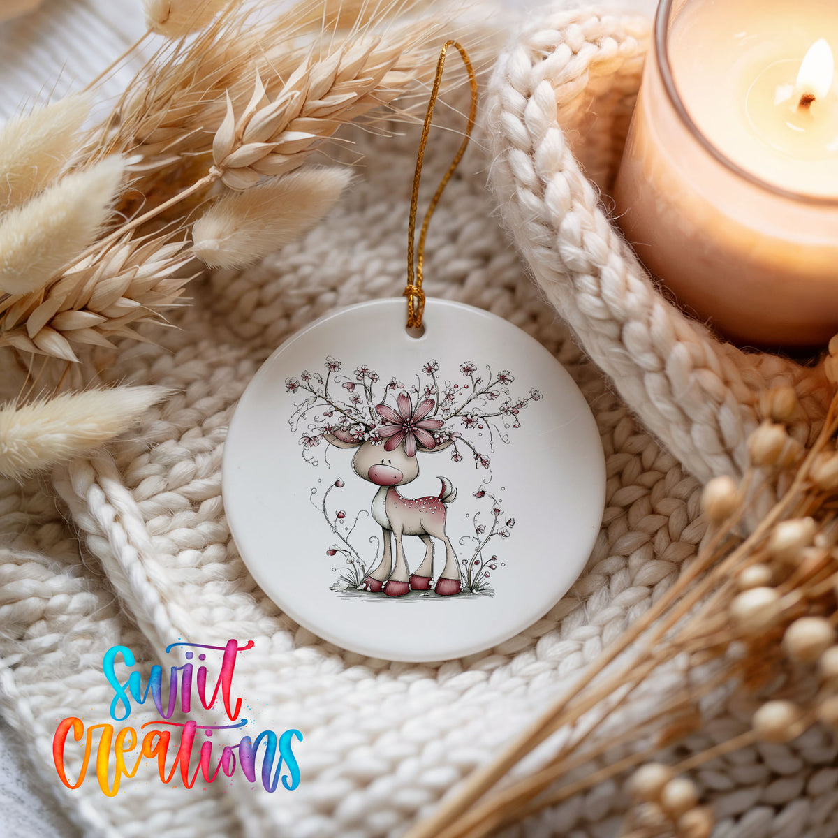 pink reindeer with snowy floral antlers ceramic Christmas ornament styled on a cozy knit blanket