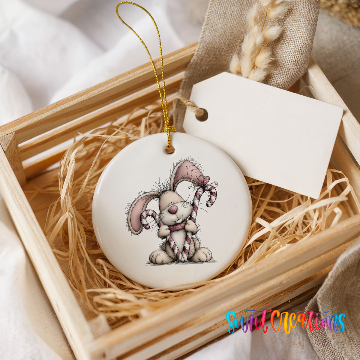 pink rabbit holding a candy cane ceramic Christmas ornament displayed in a wooden gift crate