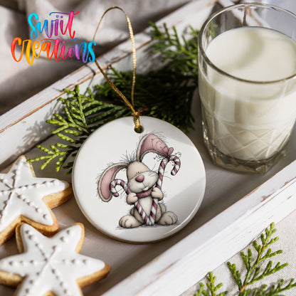 pink rabbit holding a candy cane ceramic Christmas ornament styled with holiday cookies and a candle