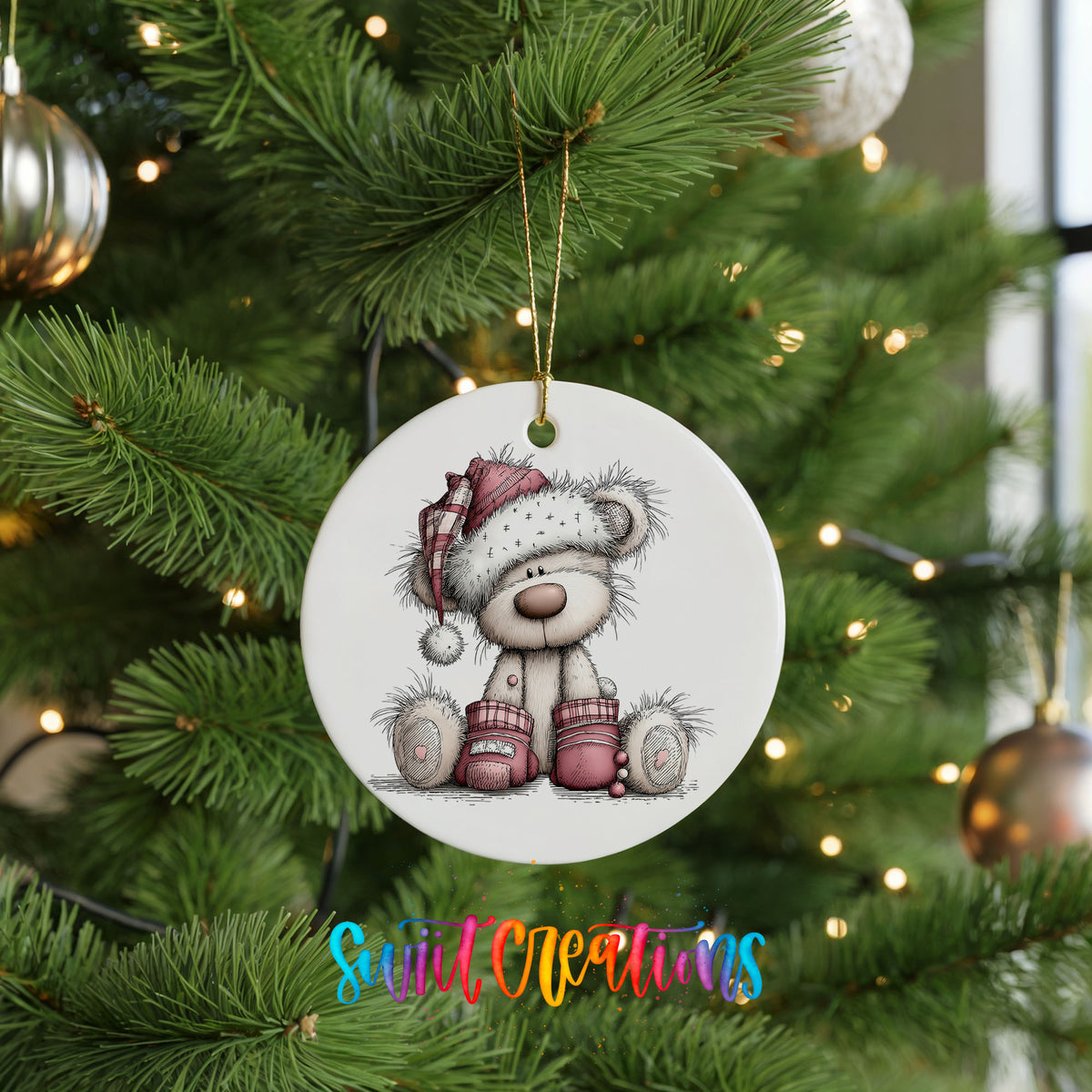 teddy bear in a Santa hat with Christmas gifts ceramic Christmas ornament hanging on a lit Christmas tree
