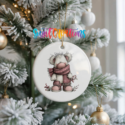 teddy bear in a pink winter sweater with holly ceramic Christmas ornament hanging on a frosted Christmas tree