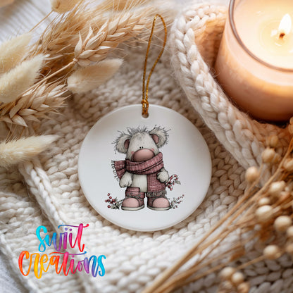 teddy bear in a pink winter sweater with holly ceramic Christmas ornament styled on a cozy knit blanket