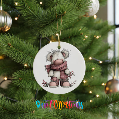 teddy bear in a pink winter sweater with holly ceramic Christmas ornament hanging on a lit Christmas tree
