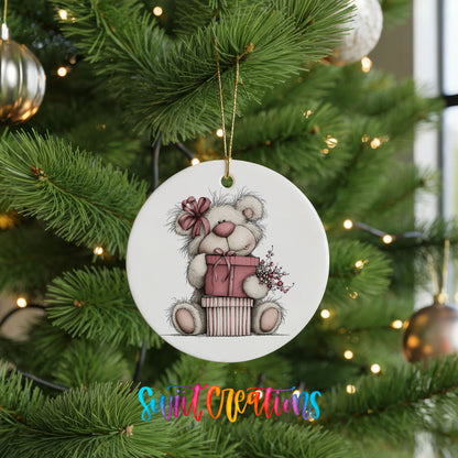 teddy bear sitting on a wrapped Christmas gift ceramic Christmas ornament hanging on a lit Christmas tree
