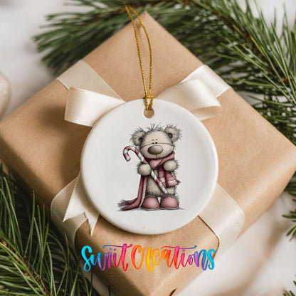 teddy bear holding a candy cane with a long winter scarf ceramic Christmas ornament displayed on a wrapped Christmas gift