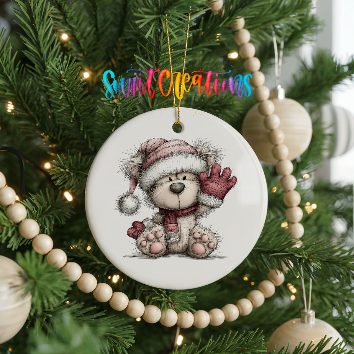 teddy bear waving beside Christmas gifts ceramic Christmas ornament hanging on a green Christmas tree