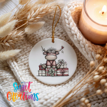 Highland cow sitting behind wrapped Christmas gifts ceramic Christmas ornament styled on a cozy knit blanket