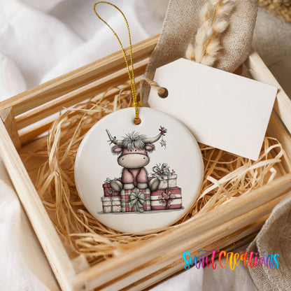 Highland cow sitting behind wrapped Christmas gifts ceramic Christmas ornament displayed in a wooden gift crate