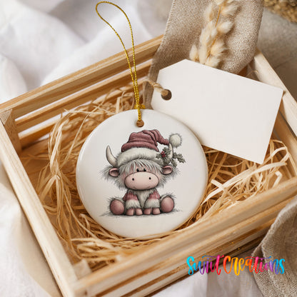 Highland cow in a pink Santa hat ceramic Christmas ornament displayed in a wooden gift crate